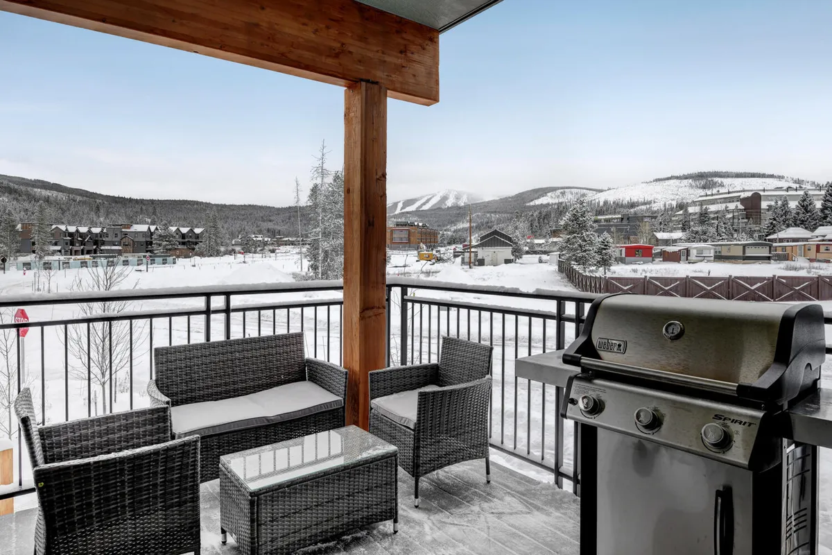 This image captures an inviting outdoor seating area with a grill set against a wintry mountain landscape. The snow-covered surroundings create a serene, resort-like ambiance ideal for social gatherings or quiet moments of relaxation. The scene embodies the idea of enjoying the outdoors in comfort, highlighting a key aspect of resort-style living at a private residence.