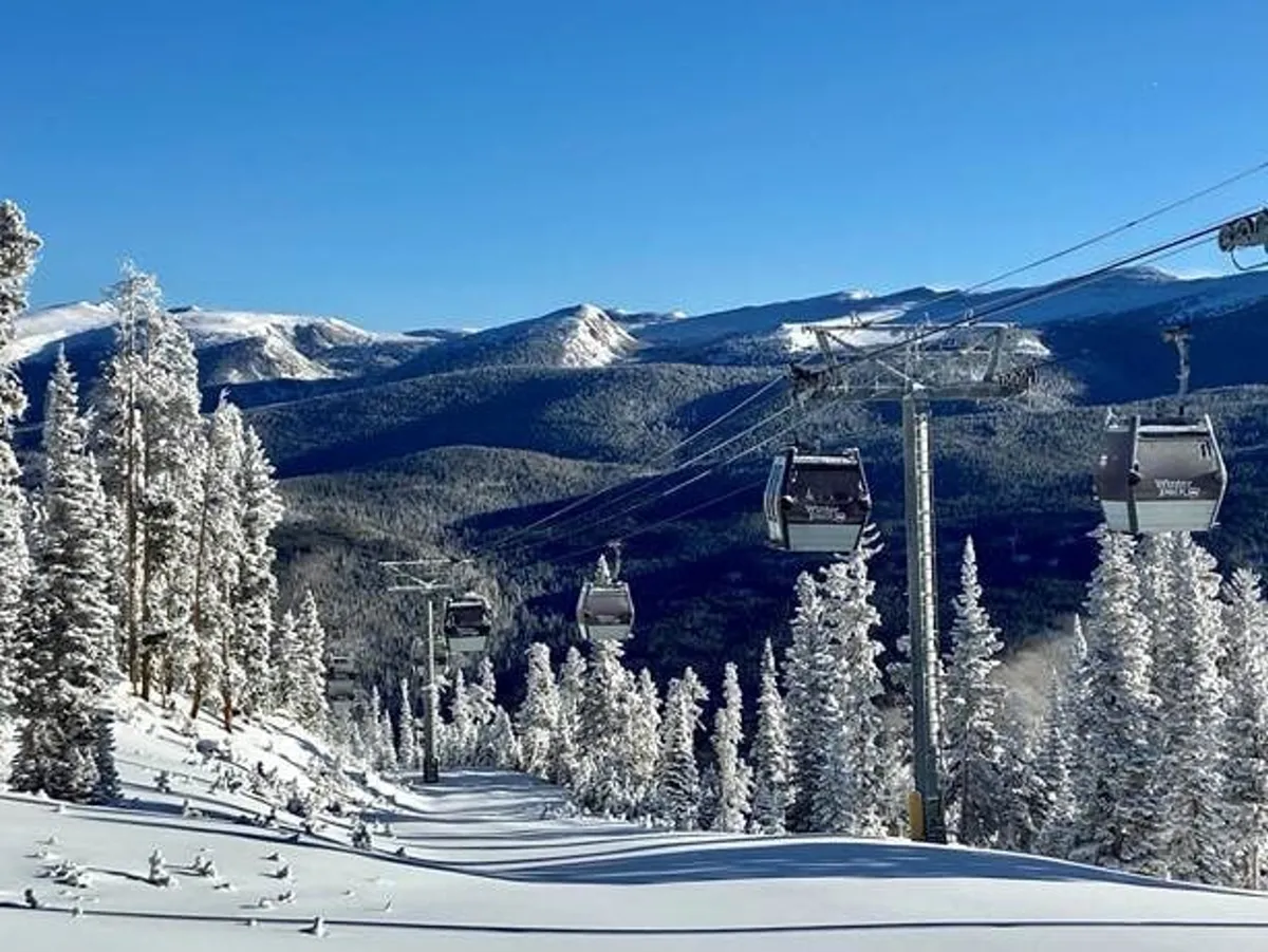 An inspiring exterior view of ski lift gondolas gliding over snow-covered slopes with distant mountains and pine trees in the background. The tranquil scene captures the anticipation and exhilaration of mountain exploration, whether for skiing, snowboarding, or simply sightseeing.
