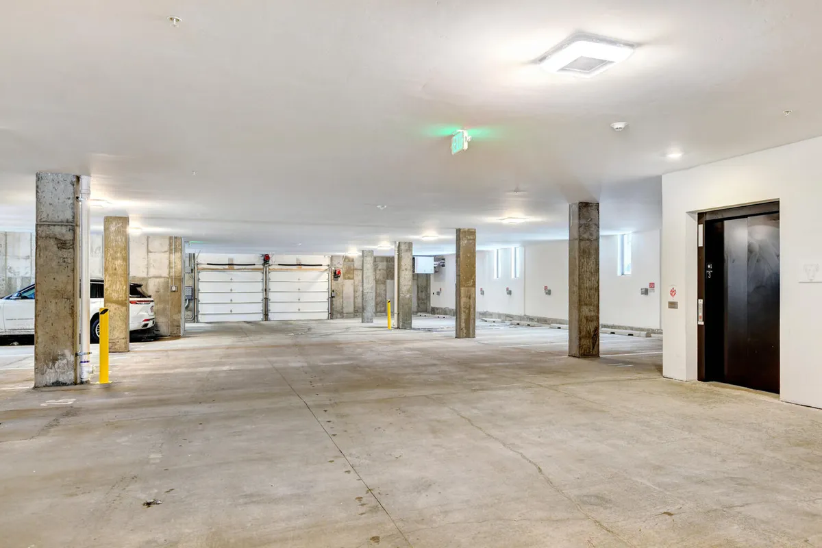 A sleek, secure underground parking area with concrete columns, garage doors, elevator access, and well-lit surroundings. The design emphasizes convenience and safety for residents and guests.