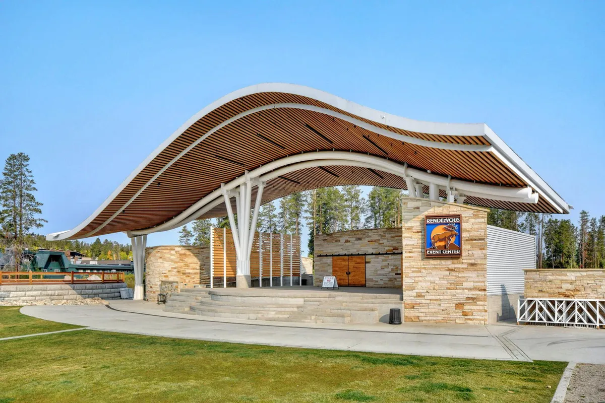 An outdoor amphitheater with a curved roof, sturdy stone walls, and steps leading up to the stage. The setting suggests it’s ready for concerts or community events, with ample space for audiences to gather and enjoy live performances.